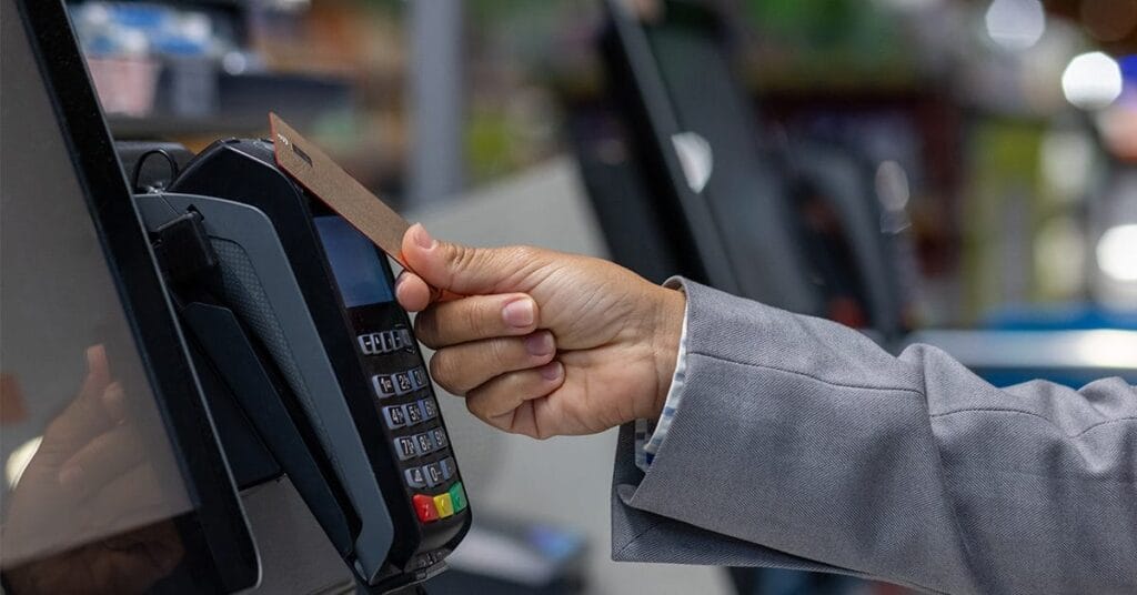 A person uses a contactless payment card at a point-of-sale terminal, highlighting reliance on cloud-first POS systems for transactions.